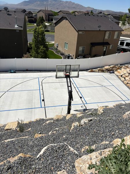 Backyard Concrete Basketball Court with Blue and Black Lines and Mountain View by Precision Pro Courts
